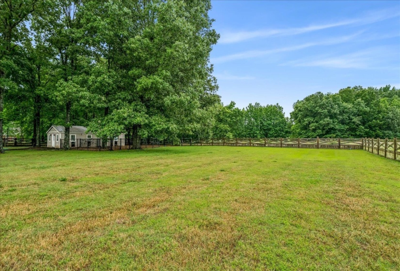 Expansive grassy area bordered by a wood rail fence