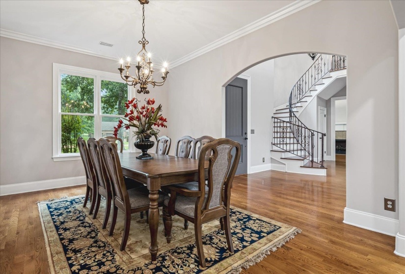 Formal dining area with hardwood flooring, a decorative chandelier, and crown molding