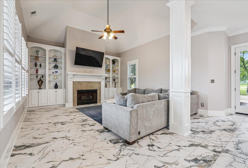 Vaulted ceiling living area featuring a central fireplace with a tile surround and mantel