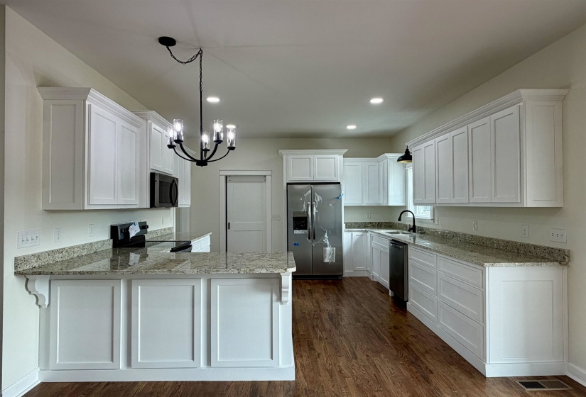 Kitchen with white cabinetry, stainless steel appliances, a peninsula, and dark wood-style floors