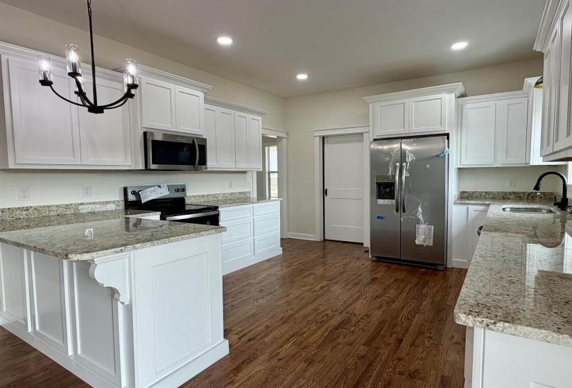 Kitchen with light stone counters, white cabinets, stainless steel appliances, and dark wood finished floors