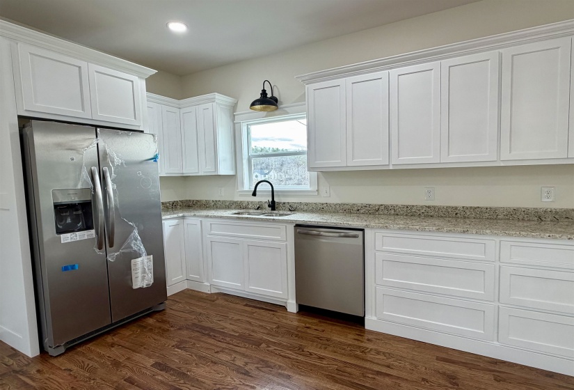 Kitchen with stainless steel appliances, white cabinetry, light stone countertops, dark wood finished floors, and recessed lighting