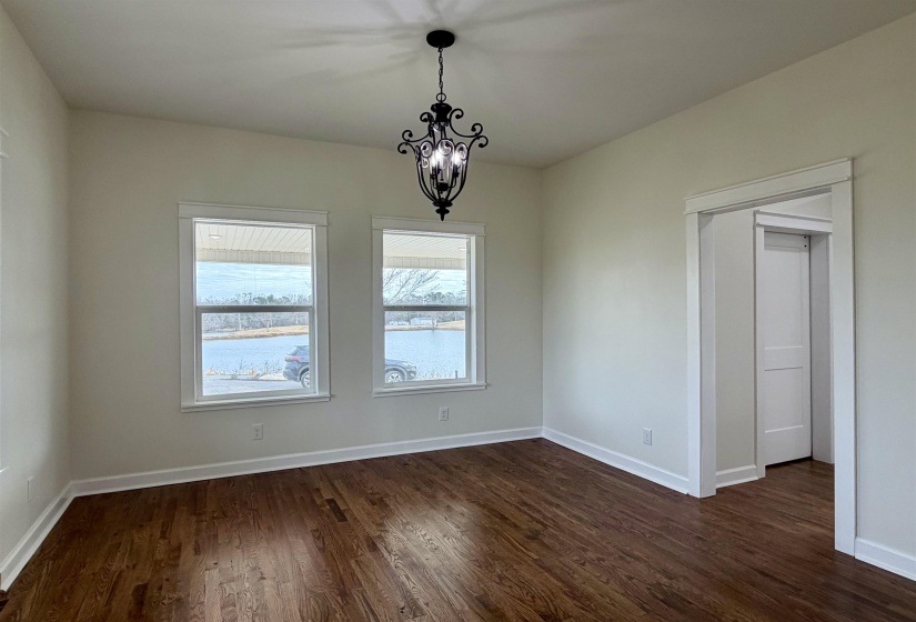 Unfurnished dining area featuring hanging lights, dark wood-style flooring, and a water view