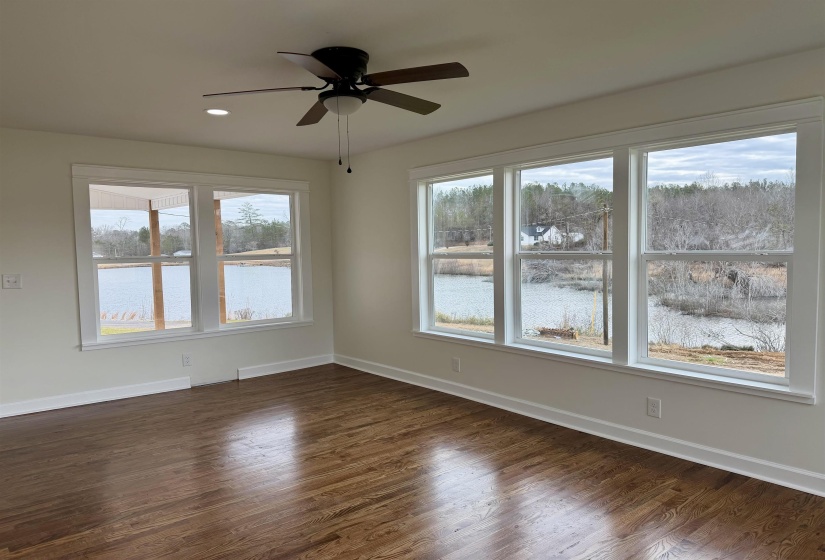 Unfurnished room with dark wood-style flooring, recessed lighting, a ceiling fan, and a water view