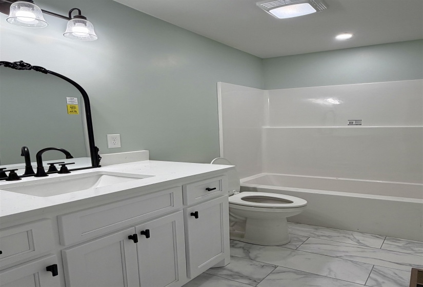 Full bath featuring vanity, bathing tub / shower combination, and light marble finish flooring