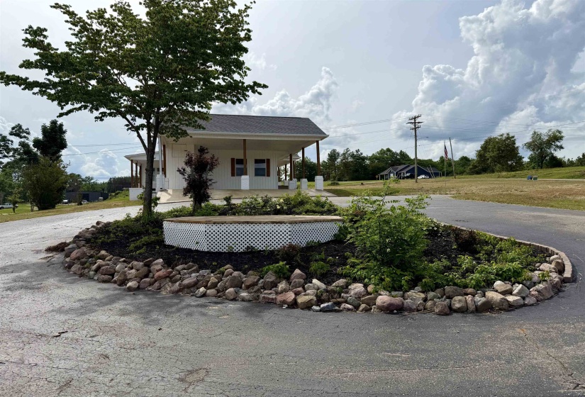 Circular driveway with a landscaped island featuring a rock border, white lattice-enclosed planter, and established plantings