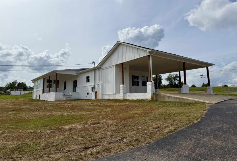 White board-and-batten siding with a covered carport featuring substantial wood support columns