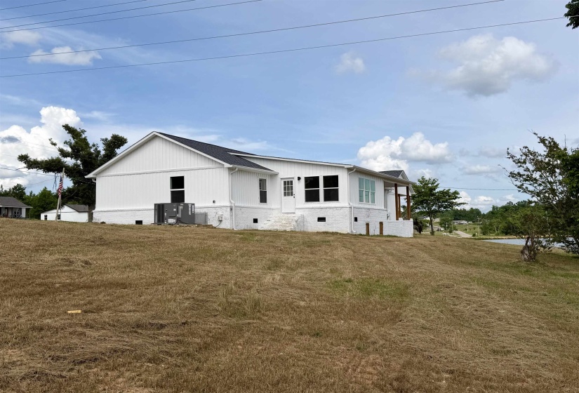 Contemporary ranch-style residence featuring white vertical siding and a dark shingle roof