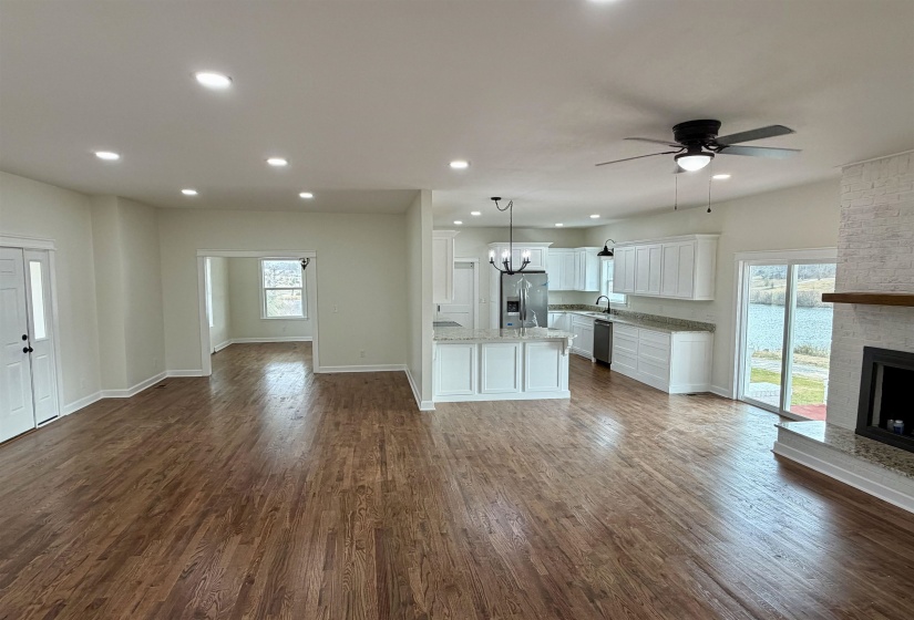 Unfurnished living room featuring dark wood-style floors, a ceiling fan, a fireplace, and a chandelier