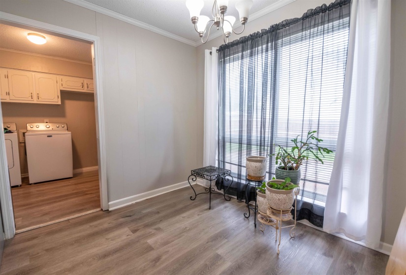 Room featuring wood-finish flooring, a chandelier, and a large window with blinds