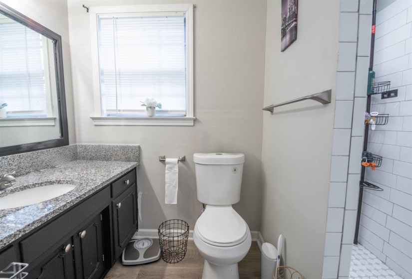Bathroom featuring a dark vanity with a granite-style countertop, undermount sink, and chrome faucet