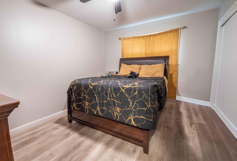 Bedroom featuring wood-finish flooring, light grey walls, white baseboards, and a ceiling fan