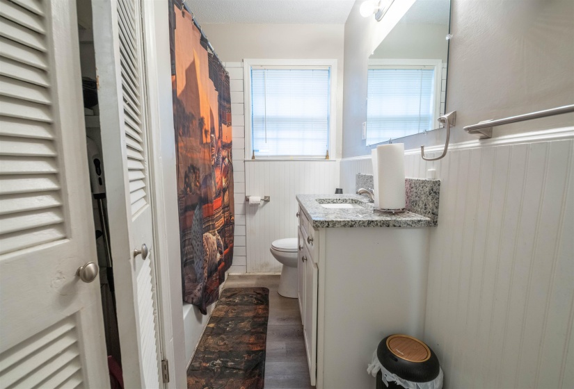 Bathroom featuring a vanity with an integrated sink, a granite countertop, beadboard wainscoting, and a wall-mounted mirror