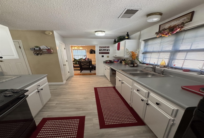 Galley kitchen featuring wood-finish flooring, white cabinetry, a double basin sink, and a black electric range