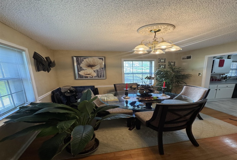 Dining area featuring wood-finish flooring, two windows with blinds, and a decorative ceiling medallion with an attached chandelier