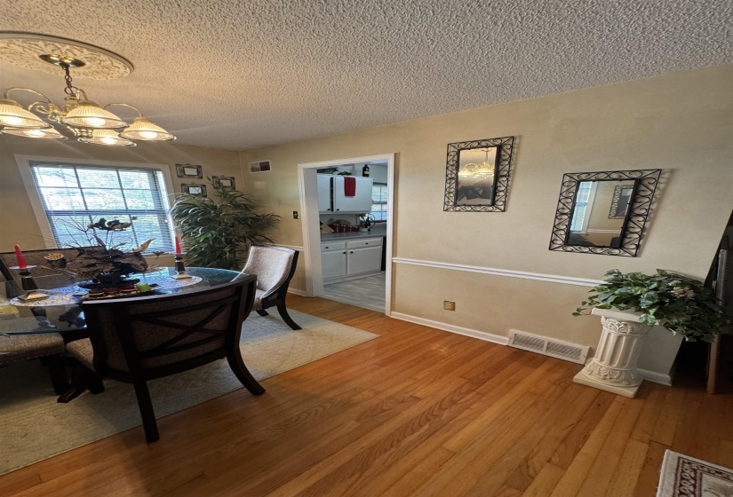 Dining area featuring hardwood flooring, a decorative ceiling medallion with a chandelier, and a chair rail molding