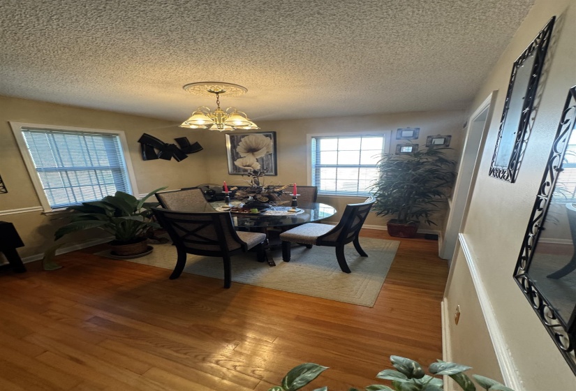 Dining area featuring light wood-finish flooring, two windows with blinds, and neutral wall tones