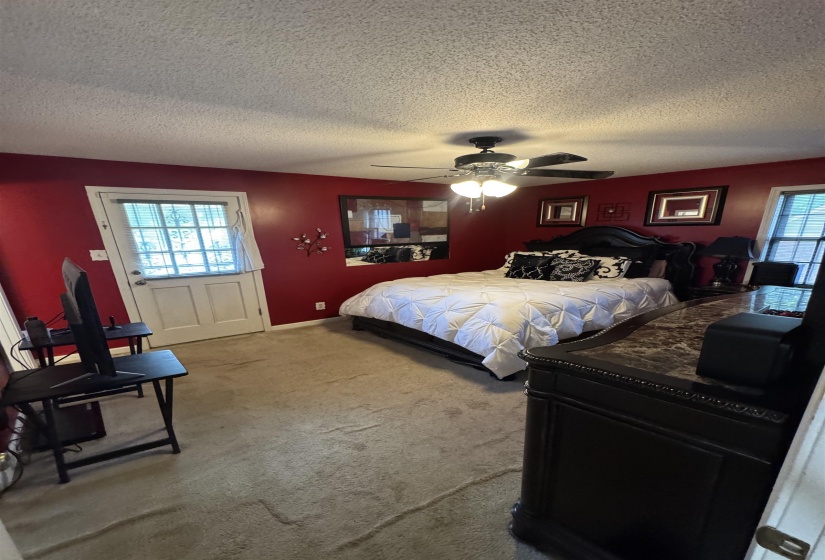 Carpeted room with a ceiling fan, a window, and a door providing exterior access