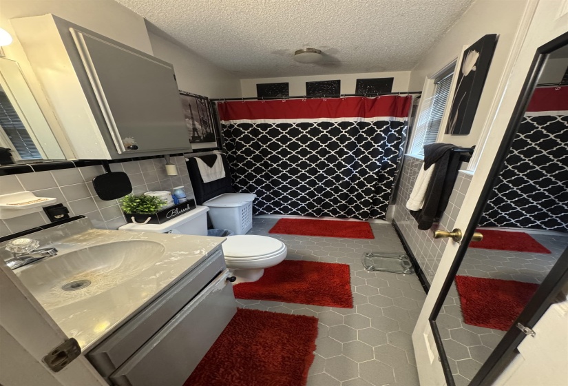 Bathroom with hexagonal tile flooring and a gray vanity featuring an integrated sink
