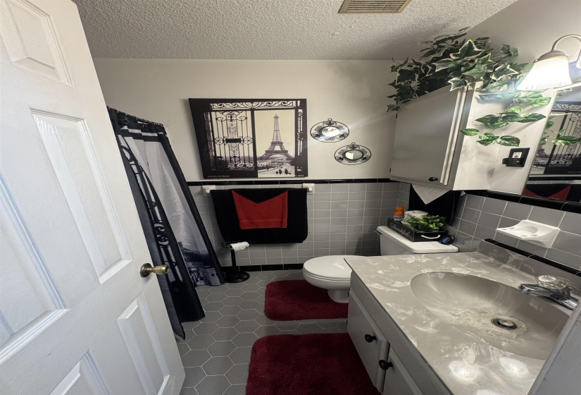Bathroom featuring grey hexagonal floor tiles, grey square wall tiles, and a white vanity with a light-toned countertop