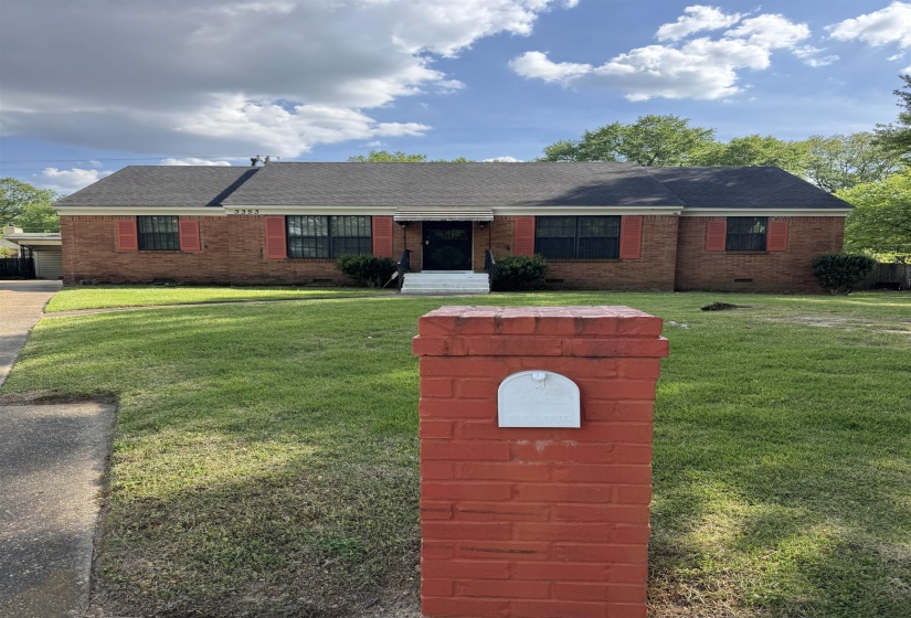 Brick exterior residence featuring a front lawn and a red brick mailbox column