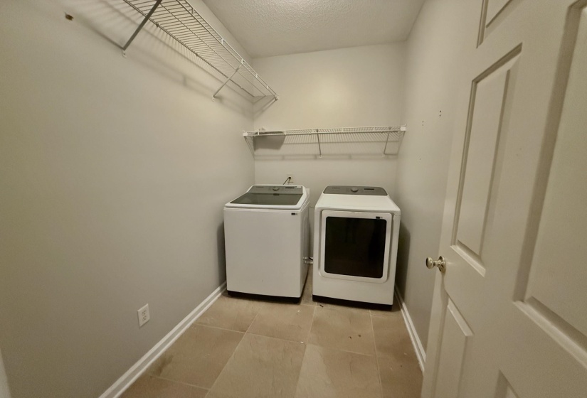 Laundry area featuring tile flooring, neutral wall color, and white wire shelving
