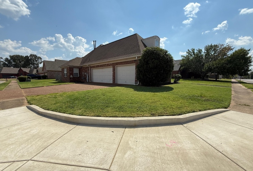 Brick exterior featuring a two-car garage with white doors, a gabled roofline, and dormer window