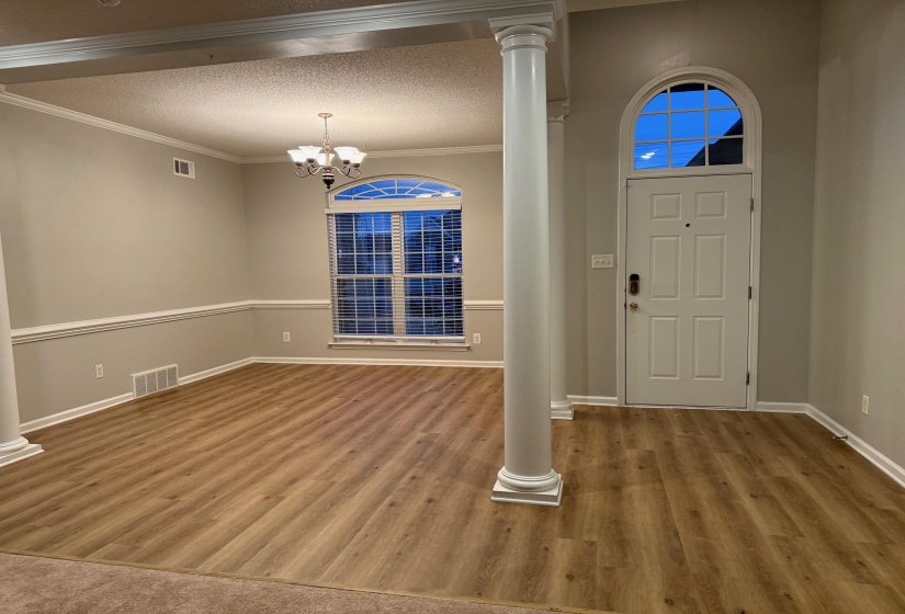 Entryway featuring a paneled door with an arched transom, wood-finish flooring, and a decorative column