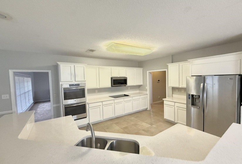 Kitchen featuring white cabinetry, light-toned countertops, tile flooring, and stainless steel appliances