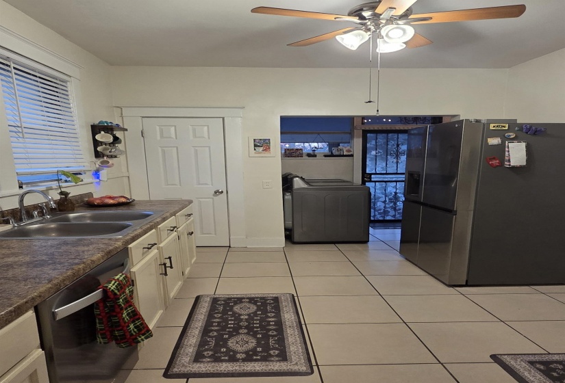 Kitchen featuring appliances with stainless steel finishes, washer / clothes dryer, light tile patterned floors, white cabinets, and dark countertops