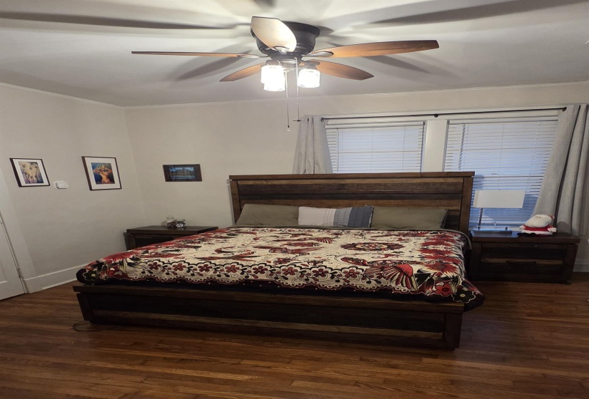 Bedroom with dark wood-style floors,  ceiling fan, smooth ceilings.