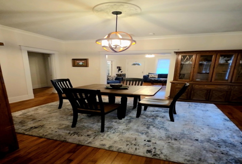 Dining room featuring dark wood finished floors, ornamental molding, and a chandelier