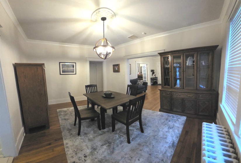 Dining area featuring radiator heating unit, dark wood-style floors, ornamental molding, and a chandelier