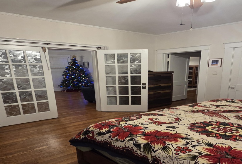 Bedroom featuring a barn door, crown molding, dark wood finished floors, and ceiling fan