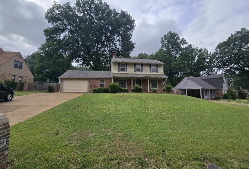 Two-story residence featuring a brick and siding exterior, an attached garage, a covered front porch with pillars, and a paved driveway