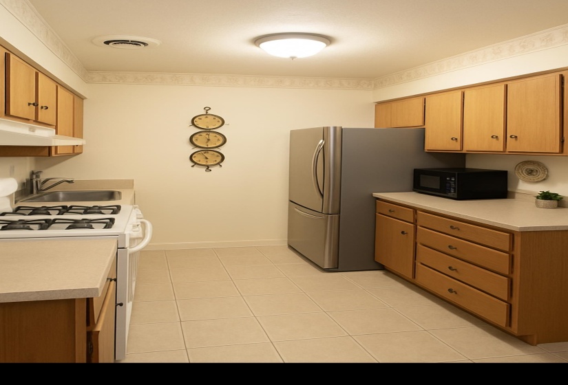Kitchen featuring white gas stove, light countertops, black microwave, under cabinet range hood, and light tile patterned floors
