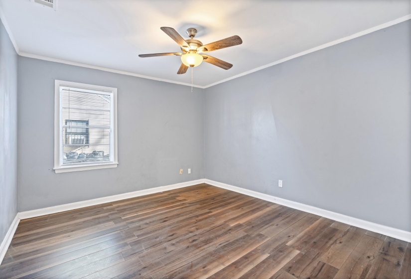 Spare room with dark wood-style flooring, ornamental molding, and a ceiling fan