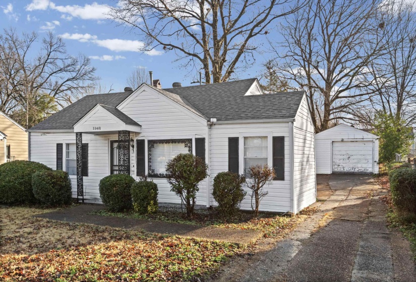 View of front of house with an outbuilding, a detached garage, a shingled roof, and driveway