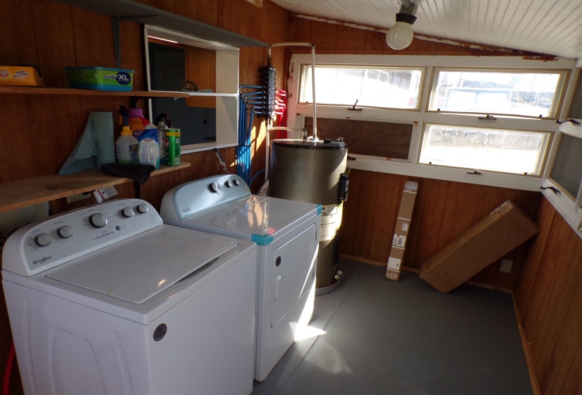 Laundry area with electric water heater, lofted ceiling, wood walls, and washing machine and clothes dryer