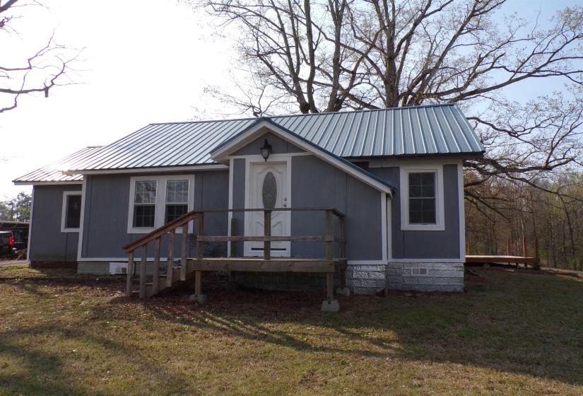 View of front of property featuring a front lawn and a metal roof