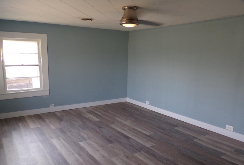 Empty room featuring dark wood-style flooring and a ceiling fan