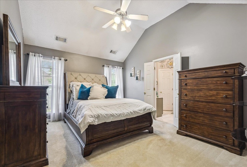 Carpeted room featuring vaulted ceilings and a ceiling fan with light fixture