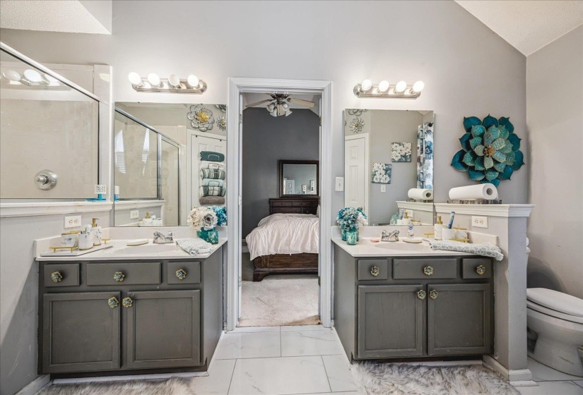 Dual vanity setup featuring gray cabinetry with ornate hardware, white countertops, and integrated sinks
