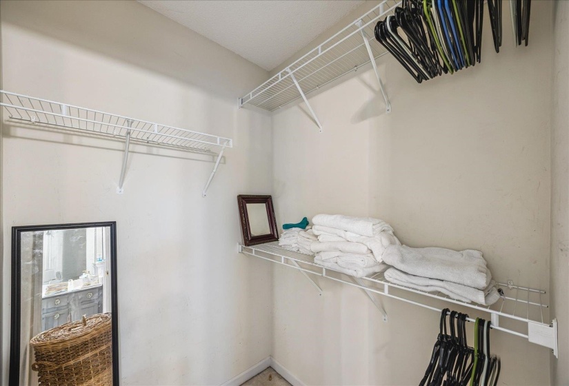 Walk-in closet featuring white wire shelving and hanging rods