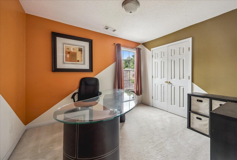 Versatile room featuring light-toned carpet flooring, a window with curtains, and white bi-fold doors