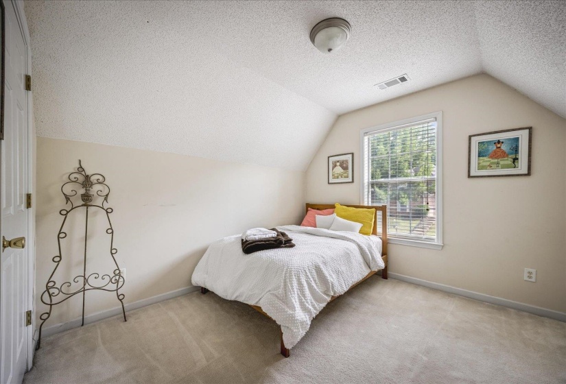 Carpeted room featuring an angled ceiling and a white door with brass hardware