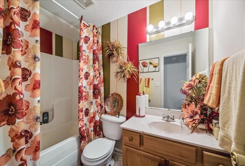 Bathroom featuring a white bathtub, toilet, and a single vanity with wood-finish cabinetry