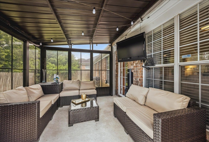 Covered patio featuring a solid roof, string lighting, and an exterior mounted television