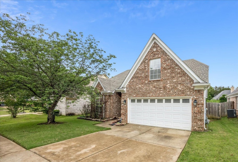 Brick exterior with a prominent front-facing gable, white paneled garage door, and a concrete driveway