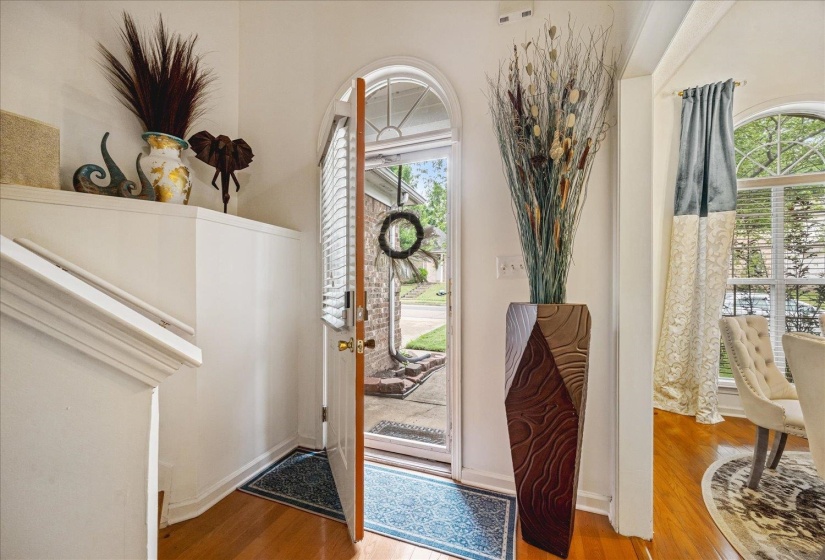 Entryway featuring warm wood-finish flooring and a white painted stairway with decorative trim